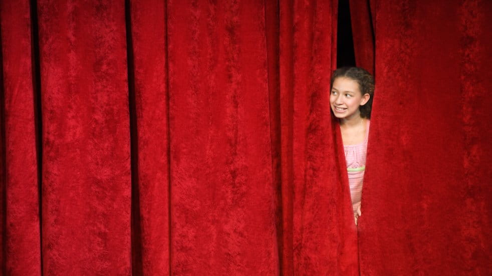 girl peeping through stage curtains